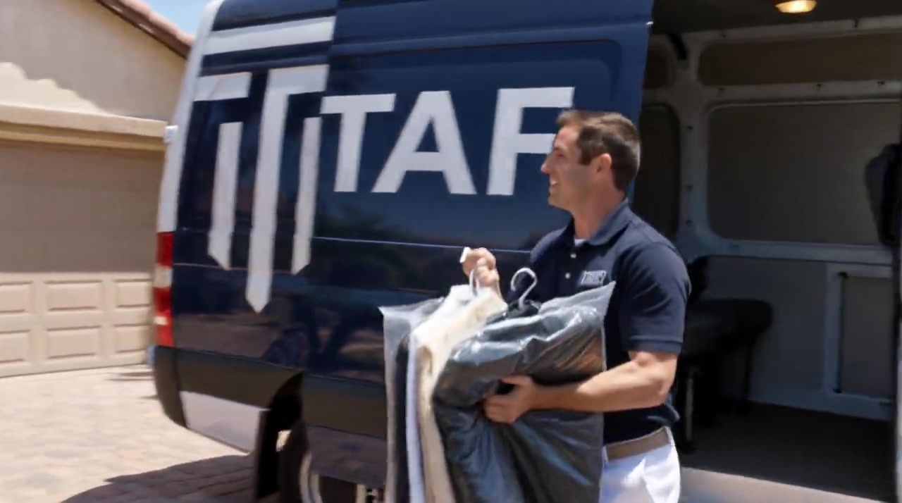Taft Dry Cleaners driver stepping out of the delivery van with freshly cleaned, bagged garments in Orange, CA